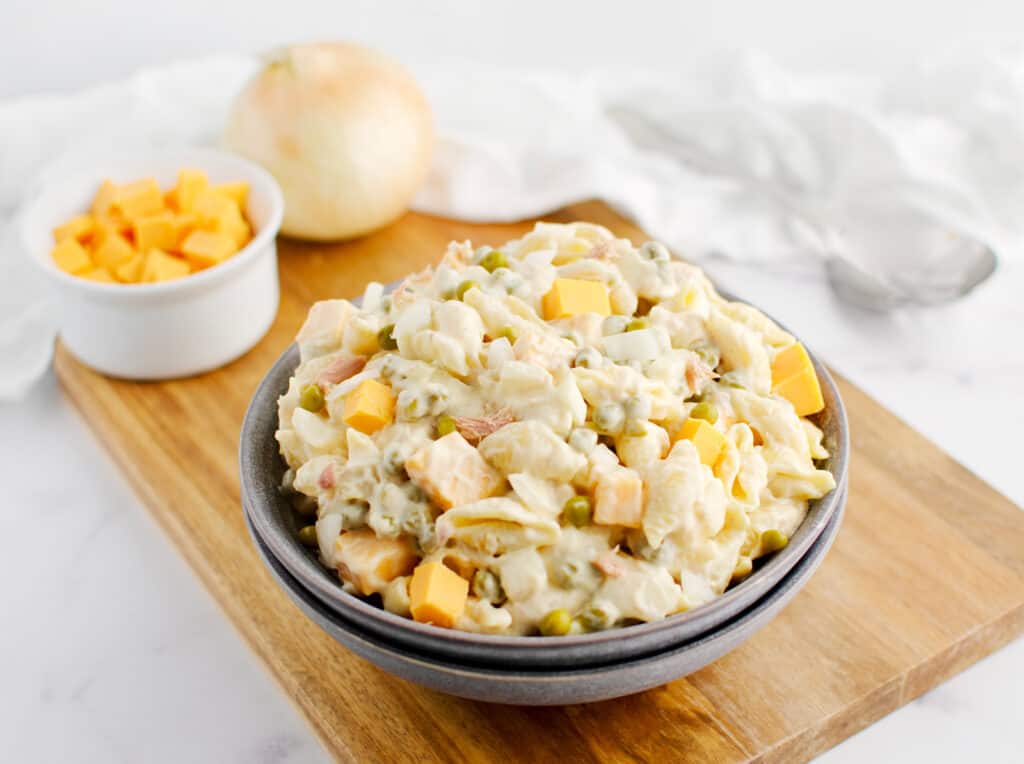 Tuna Pasta Salad with Cheese and Peas in Bowl on Wooden Cutting Board