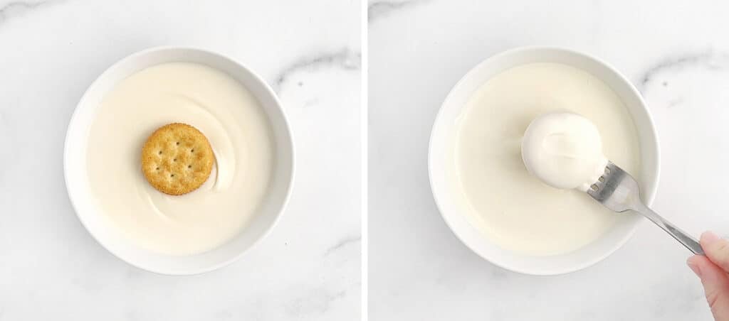 Dipping Cracker Cookies Into Melted White Chocolate in Bowl on Marble Surface