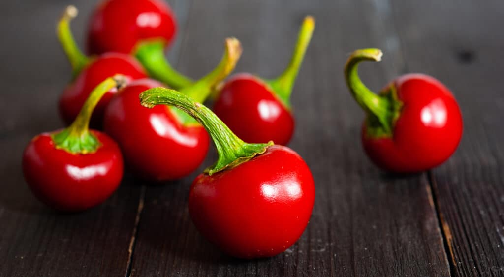 Fresh cherry peppers on a dark wooden surface