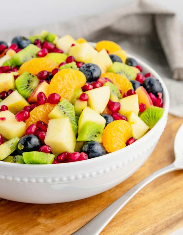 Winter Fruit Salad in White Bowl on Wooden Surface with Serving Spoon